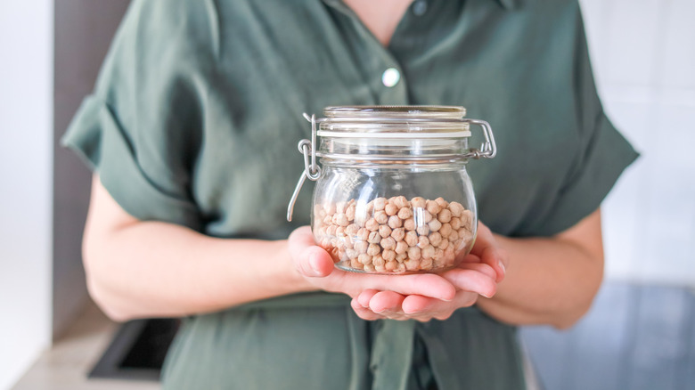 pregnant woman holding a jar of dried chickpeas