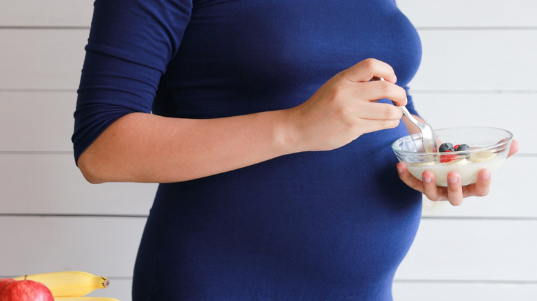 pregnant woman eating a yogurt bowl