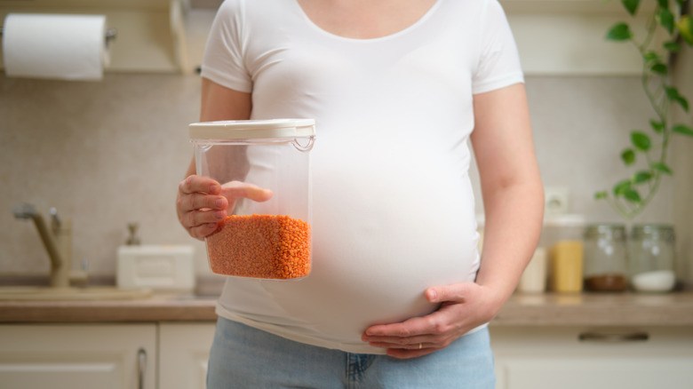 pregnant woman holding container of red lentils