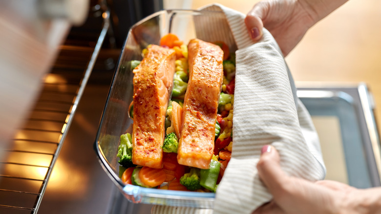 woman removing cooked salmon from the oven