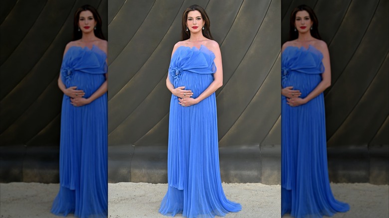 Anne Hathaway poses with her baby bump in a blue dress