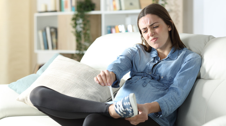 pregnant woman struggling to put on shoe