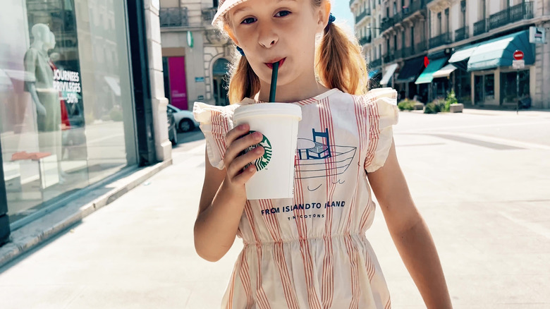 Young girl sipping from Starbucks cup with straw