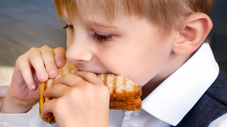 Kid eating grilled cheese sandwich