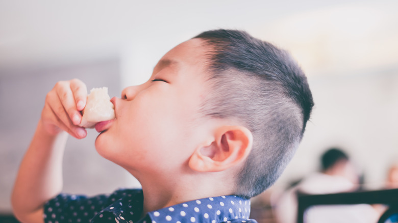 Little boy eating a snack that looks like a scone