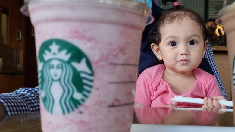 Toddler looking at a pink Starbucks drink
