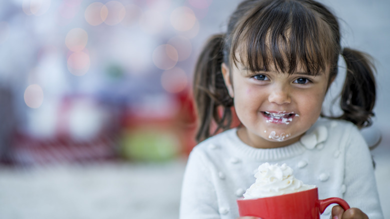 Little girl enjoying mug of whipped cream