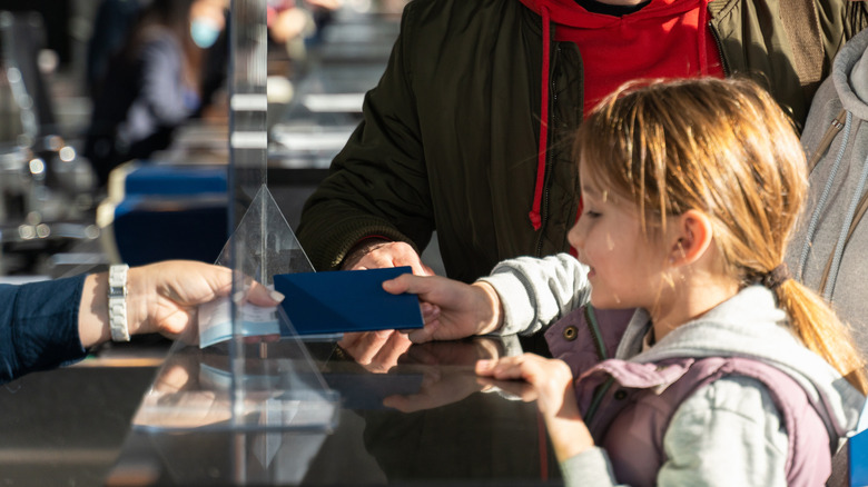 child handing over passport in airport