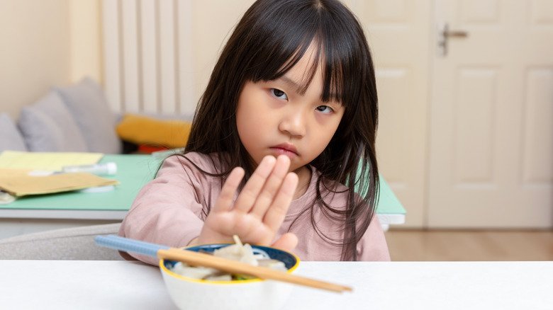 child pushing back a bowl of food