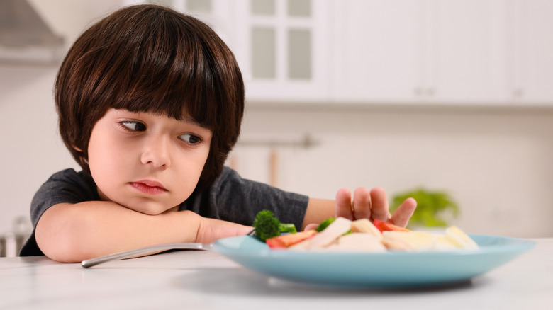 child side-eyeing a plate of food