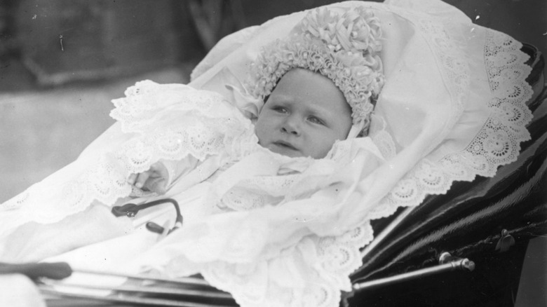 King George VI riding in a baby carriage and looking serious