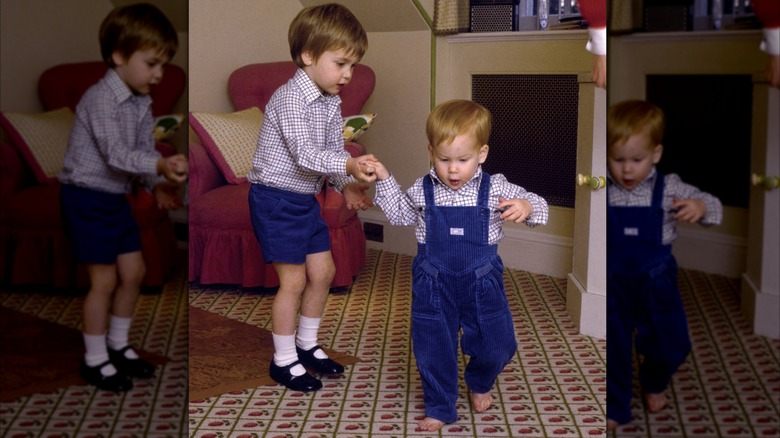 William, Prince of Wales holding Prince Harry's hand while he learns to walk