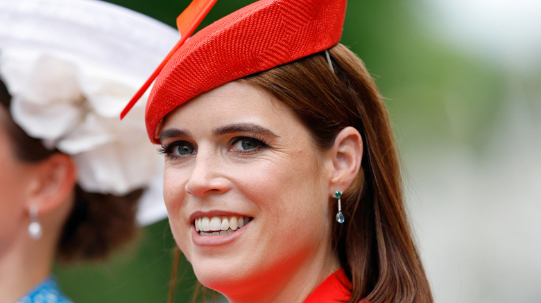 Princess Eugenie smiling and wearing red fascinator