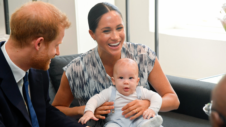 Meghan Markle holds Prince Archie of Sussex while Prince Harry looks on