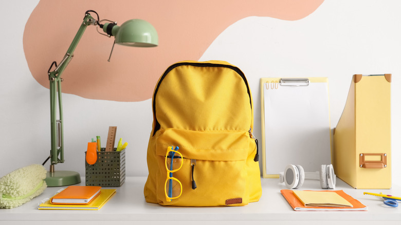 Desk setup with a backpack, headphones, and various school supplies