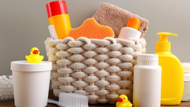 Bath time soap and supplies in unlabeled white and yellow plastic bottles in and around a soft woven basket