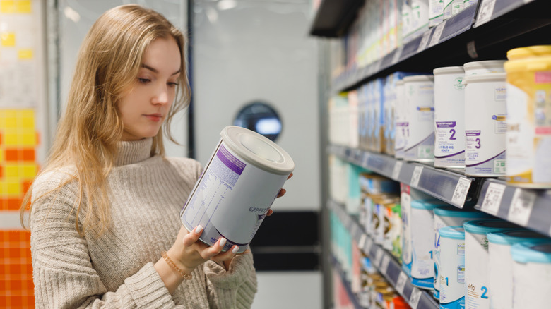 Woman looking at can of formula