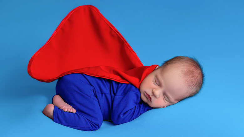 Sleeping baby in superhero onesie with red cape