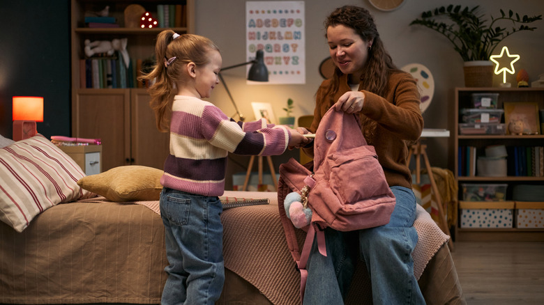 mom and daughter packing backpack at night