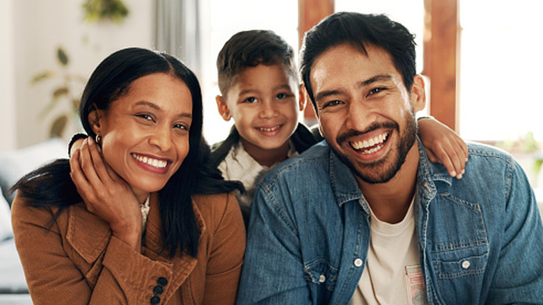 Parents smiling with their child peeking out behind them