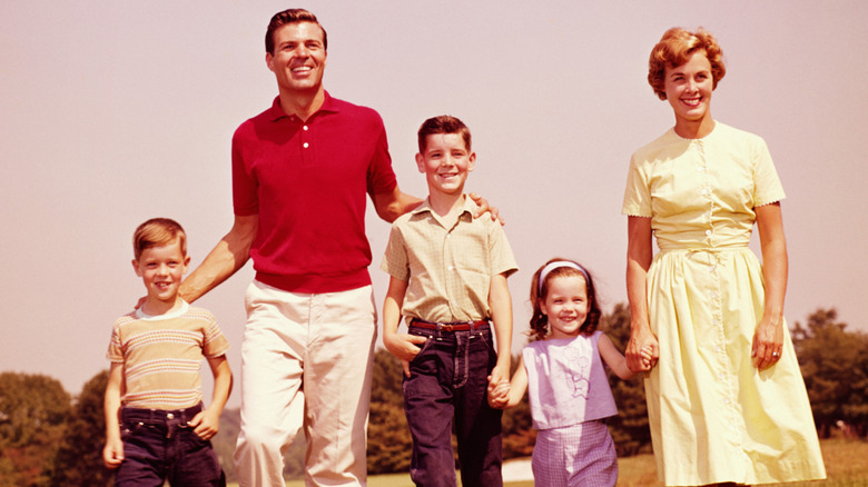 1960s family smiling and walking with their three kids