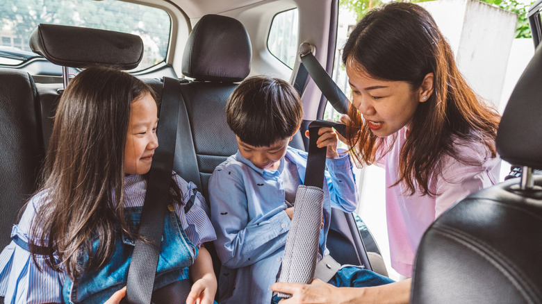 Mother buckling children into car seat