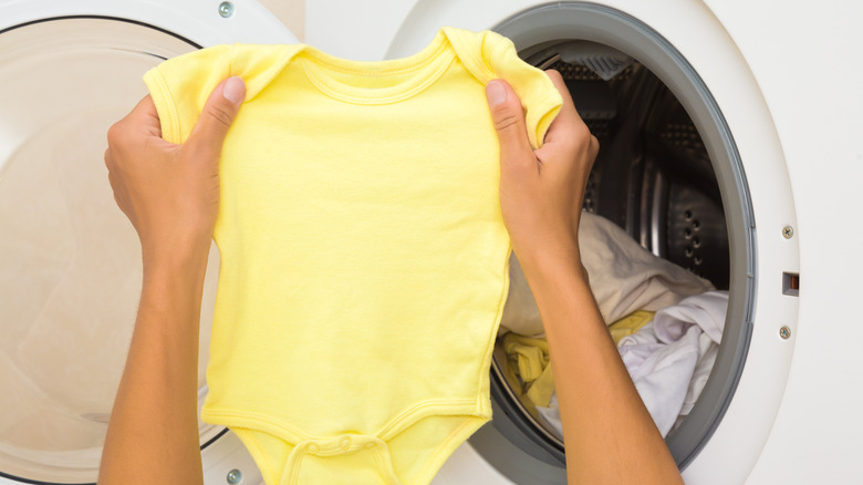 Close-up of hands taking a onesie out of a washing machine