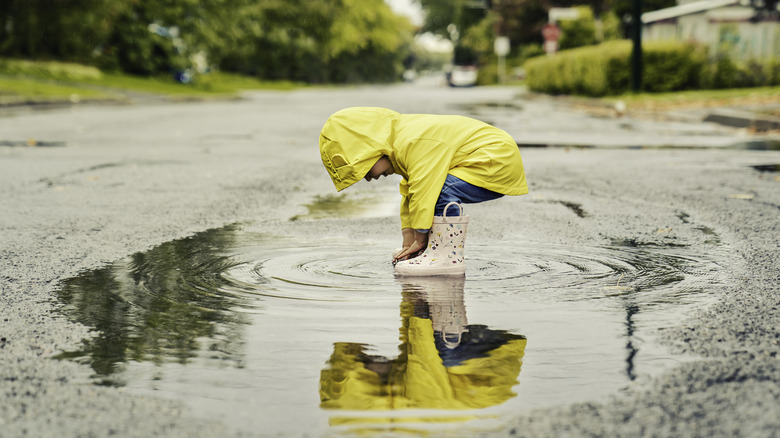 child splashing in a rain puddle