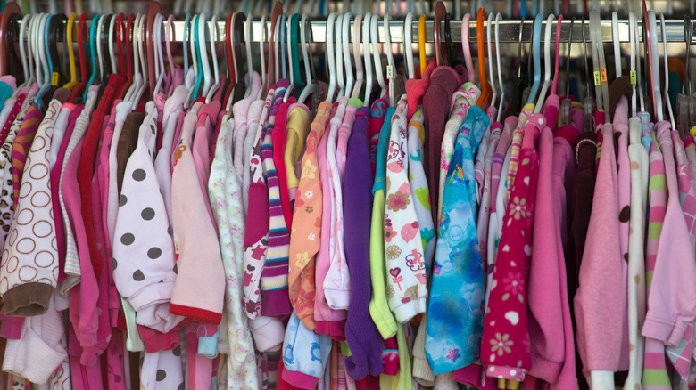 Rack of little girl's pajamas and onesies handing in a thrift store