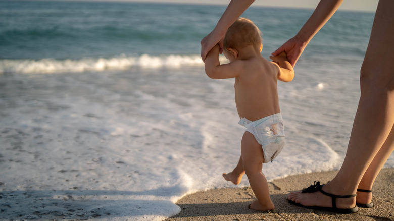 Child in diaper walking on beach