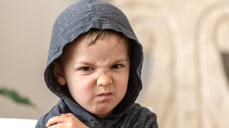 toddler looking unhappy while wearing a hoodie