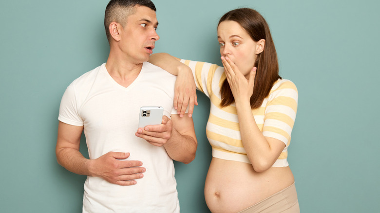 surprised pregnant couple looking at the phone