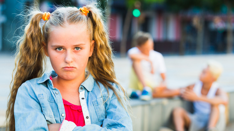 young girl looking angry with other kids in the background at a playground