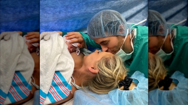 Enrique Iglesias kisses Anna Kournikova as they hold a newborn