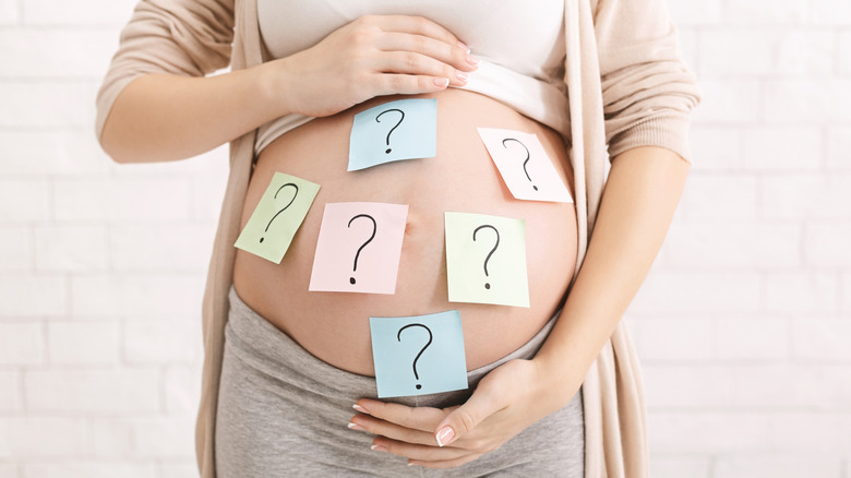 woman with question mark post-it notes all over her bump