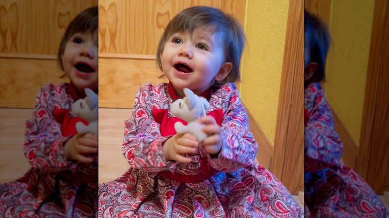 toddler holding a toy and wearing a paisley dress