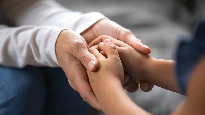 Close-up of an adult's hands cupping a child's hands