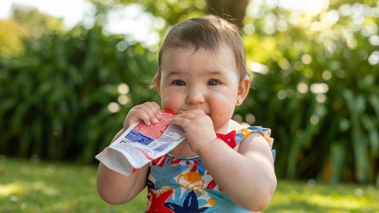 Baby eating a baby food pouch