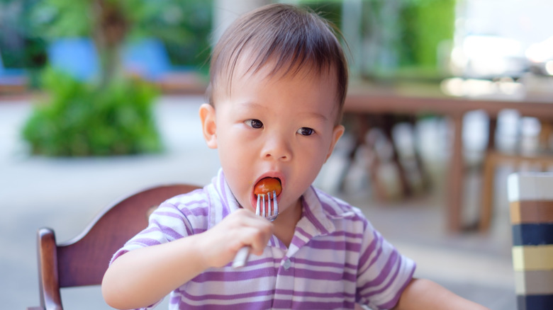 A toddler takes a bite of a meatball