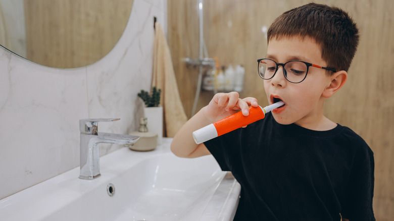 boy brushing his teeth with an electric toothbrush