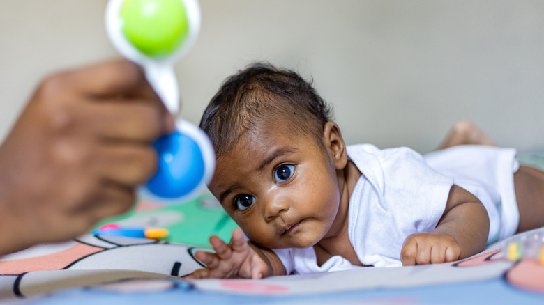 newborn baby looking up at a toy