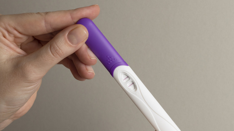 woman's hand holding a positive pregnancy test