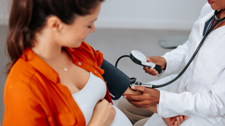 A pregnant woman has blood pressure monitored by a doctor