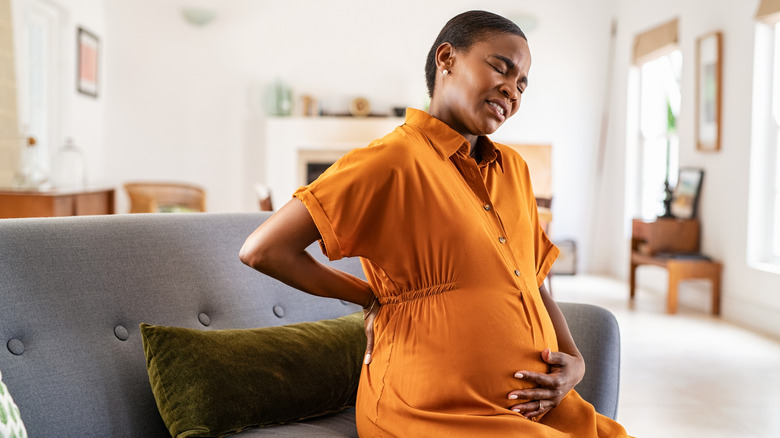 A pregnant woman sits on a couch experiencing active labor pains