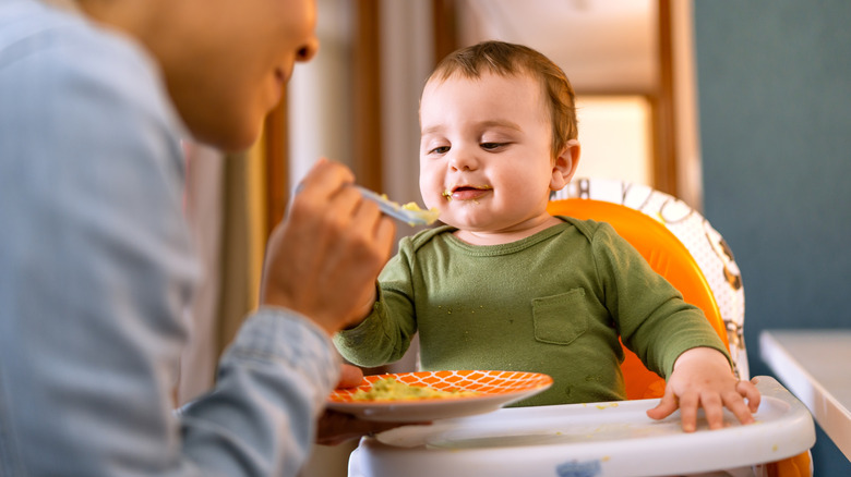 a baby seated in their high chair during mealtime