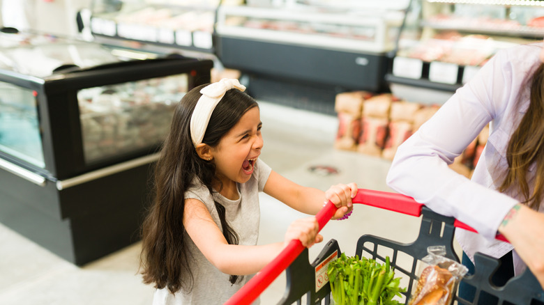 Girl crying and holding on to a supermarket cart
