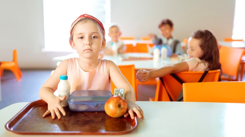 Girl in a headband sitting alone at lunch time in school