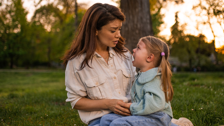 Mom holding child on her lap while kid is upset