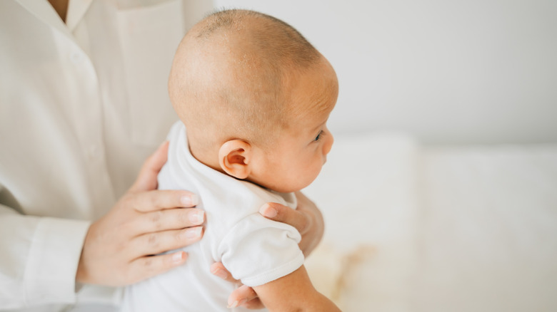 woman burping an infant in her lap