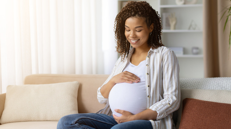 woman smiling and looking down at her baby bump